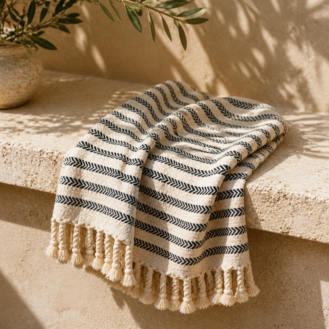 Napoli Turkish cotton towel in charcoal and cream stripe draped over a stone ledge