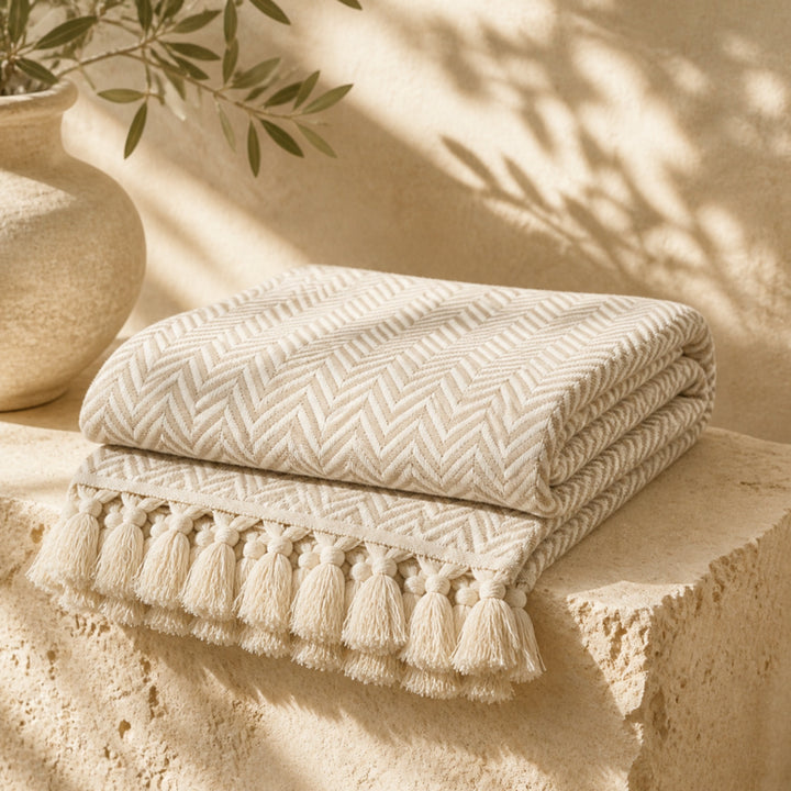 Turkish cotton herringbone throw in Milky Brown folded on travertine