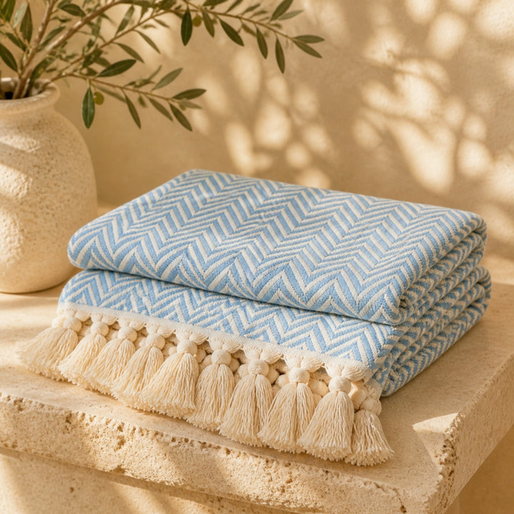 Turkish cotton herringbone throw in Sky Blue folded on travertine